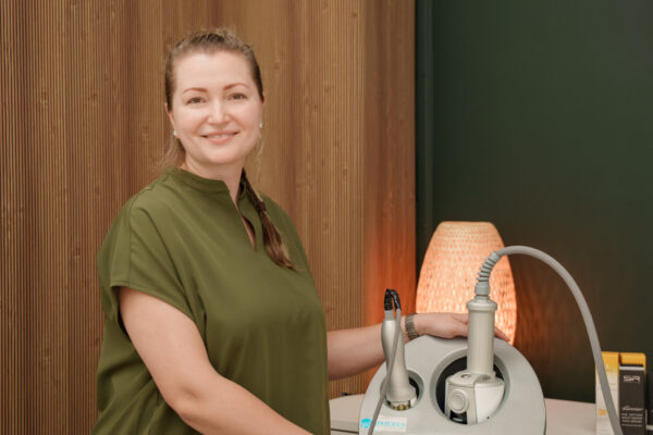 Daria Havlovskyy in olive scrubs standing at the Endosphères Therapy machine at Glow Lab