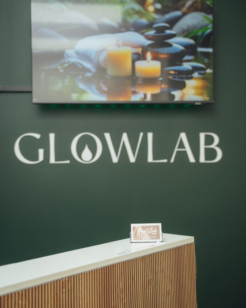 Glow Lab reception with GLOWLAB lettering on the dark green wall