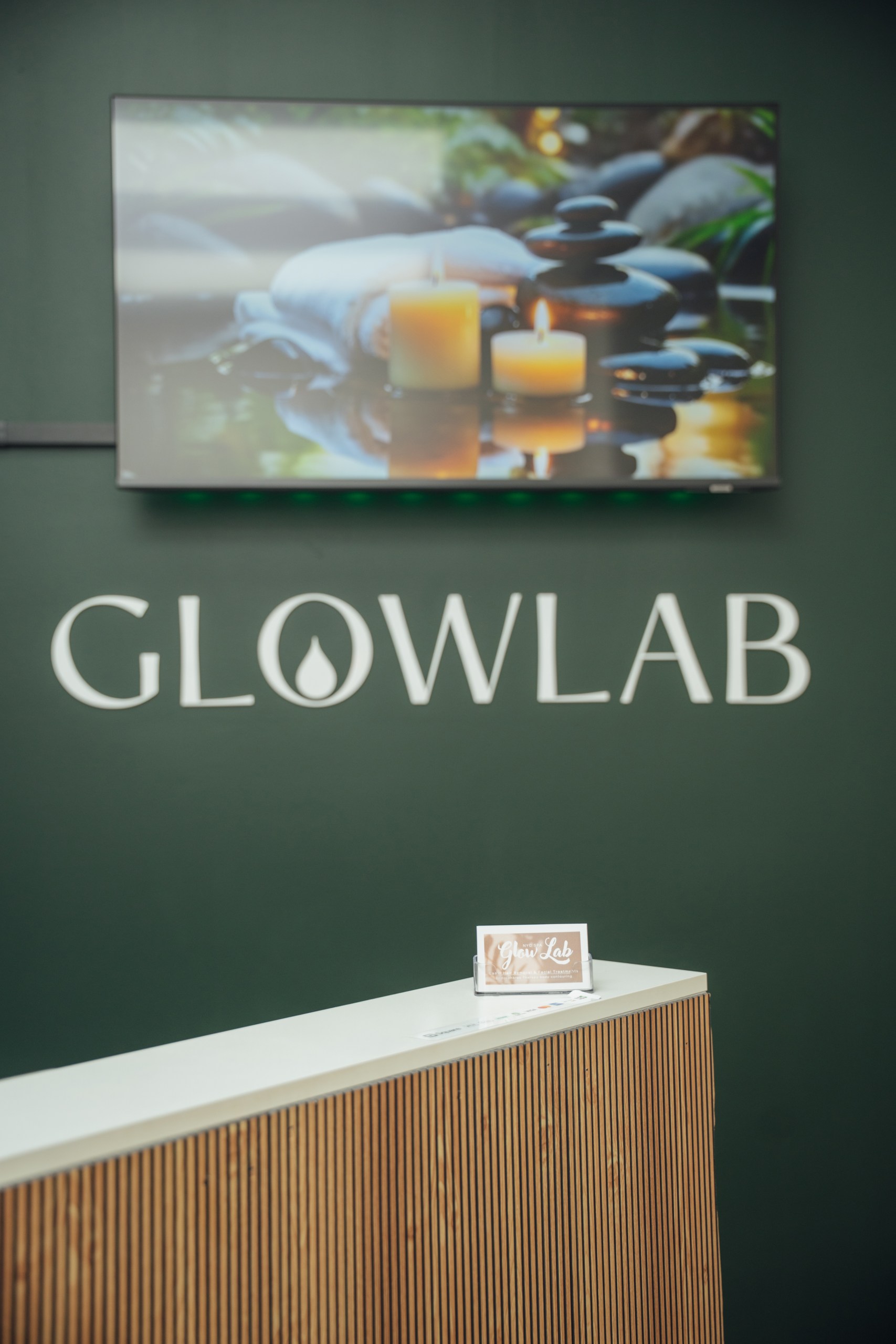 Glow Lab reception with GLOWLAB lettering on the dark green wall